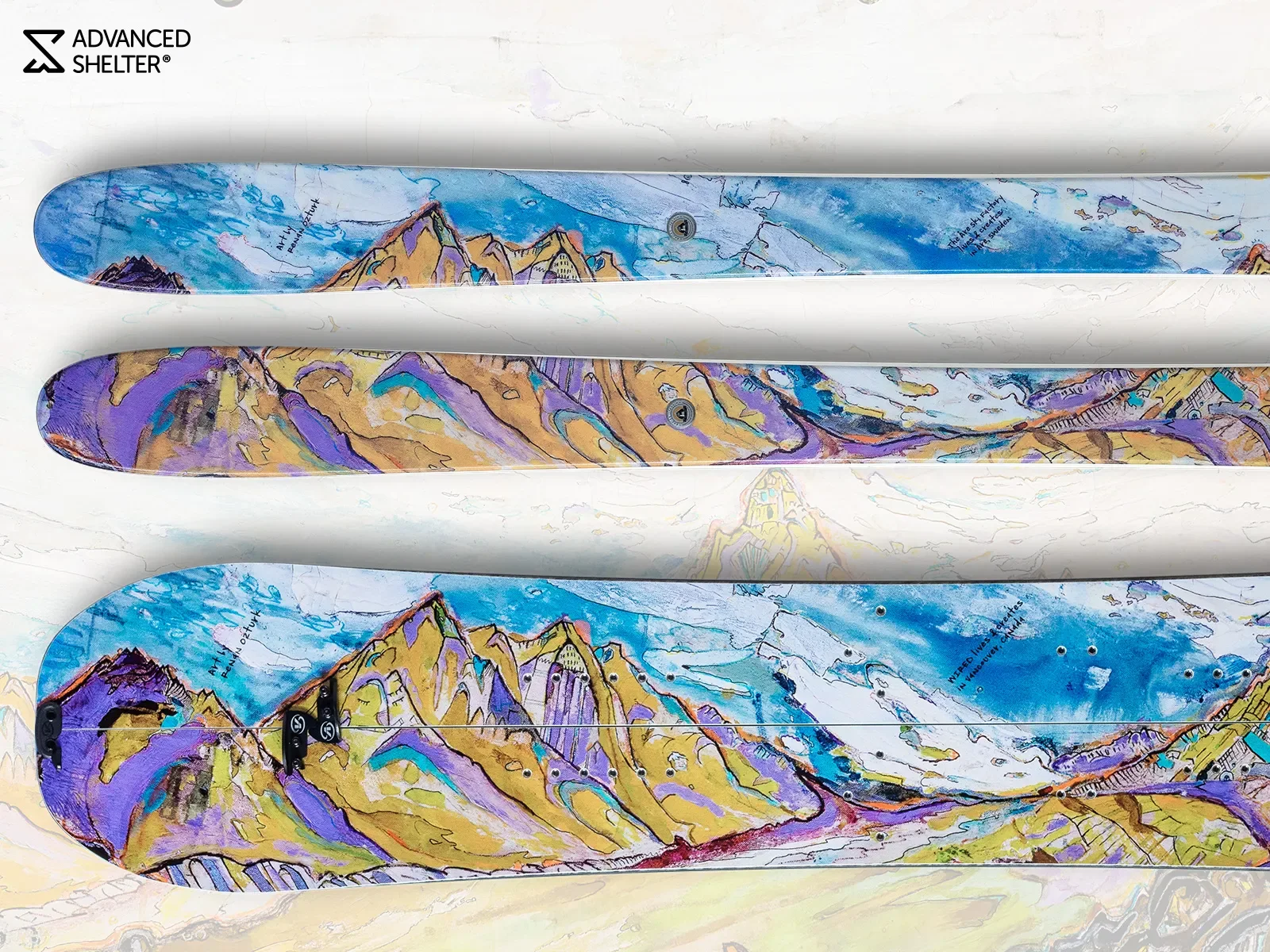 Advanced Shelter splitboard and skis carrying Renan Ozturk’s painting of yellow and violet peaks under a blue sky
