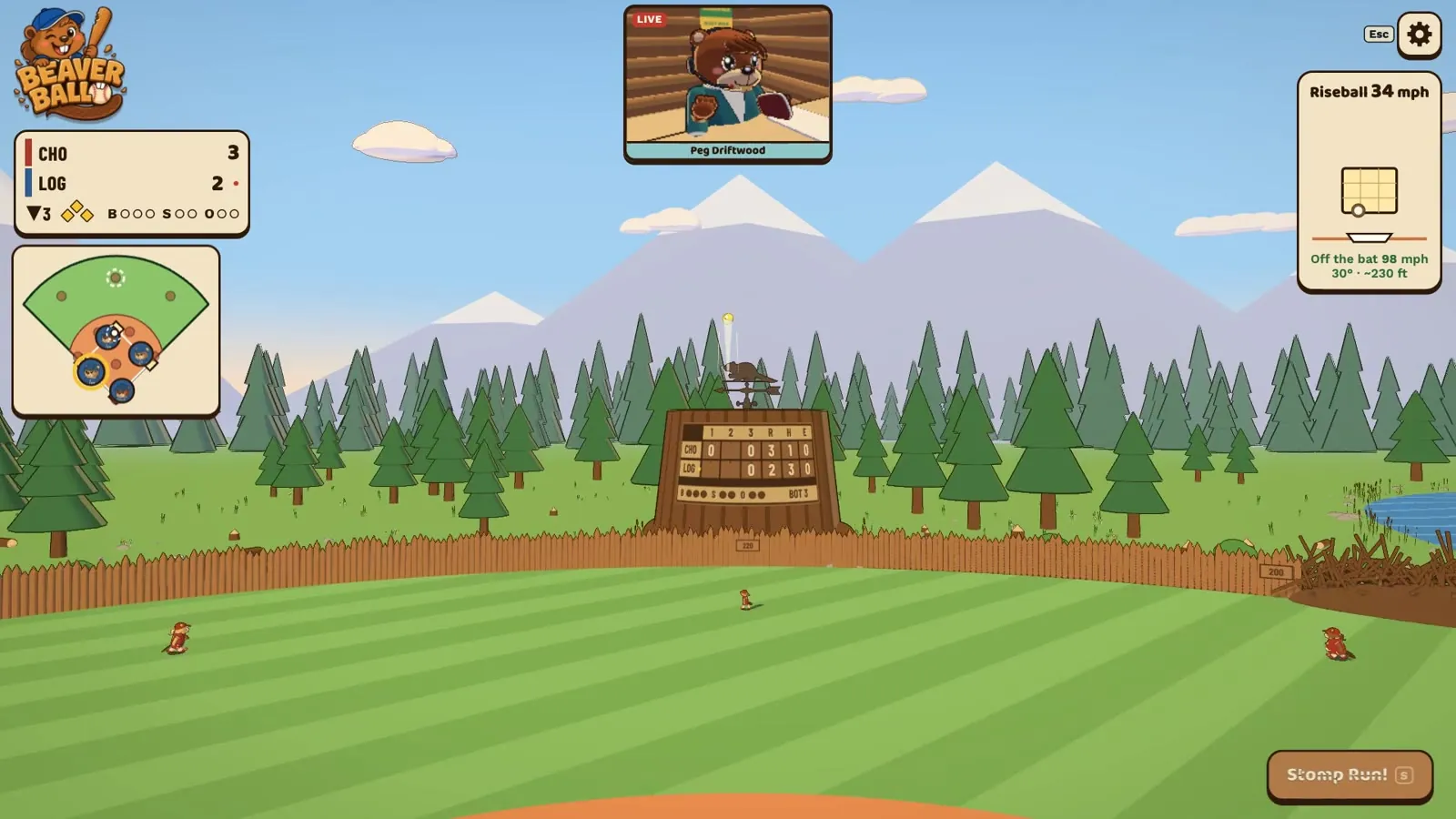 A wide view of Lodgepole Park’s outfield: green grass, a stump scoreboard, pine trees and mountains under a blue sky.